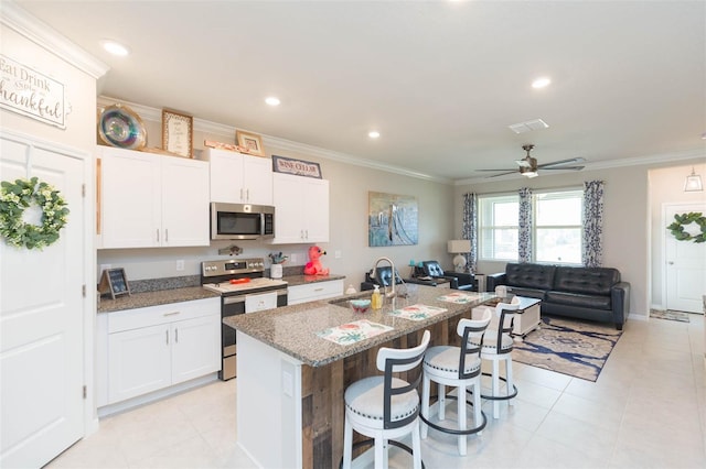 kitchen with white cabinets, stainless steel appliances, a center island with sink, and sink