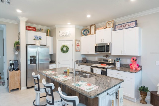 kitchen with white cabinetry, sink, stainless steel appliances, and a center island with sink