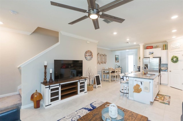 tiled living room featuring crown molding, sink, and ceiling fan