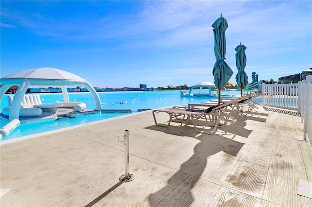 view of swimming pool featuring a water view and a patio area