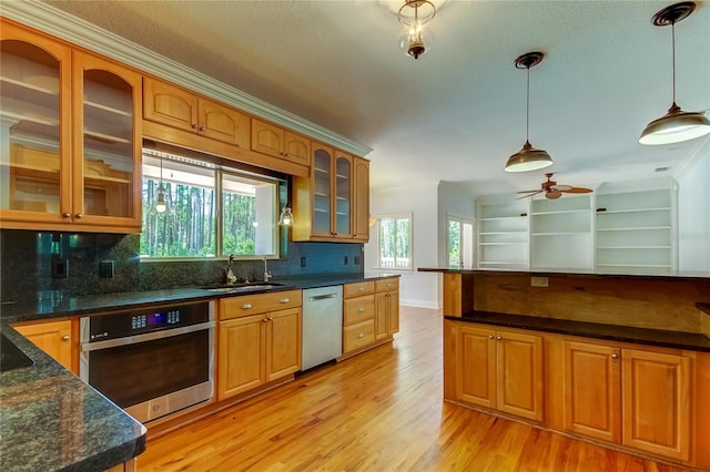 kitchen with appliances with stainless steel finishes, light wood-type flooring, ceiling fan, decorative light fixtures, and decorative backsplash