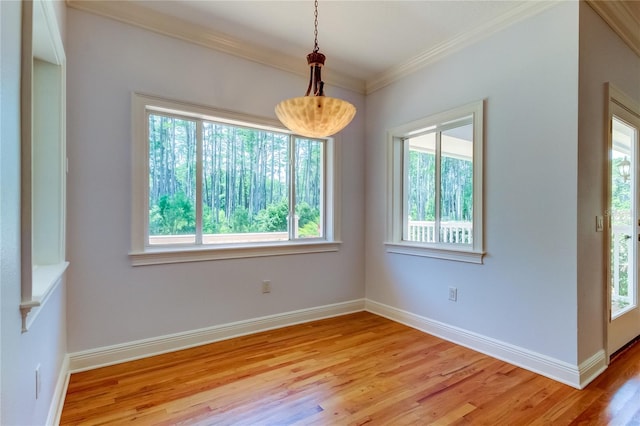 empty room featuring ornamental molding, light wood-type flooring, and a healthy amount of sunlight