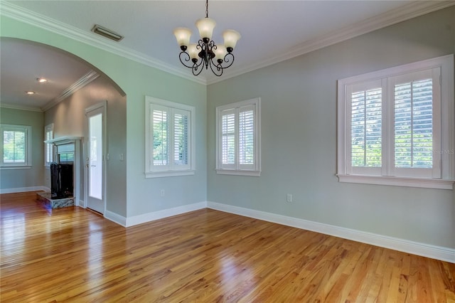 spare room featuring light hardwood / wood-style floors, ornamental molding, and a healthy amount of sunlight