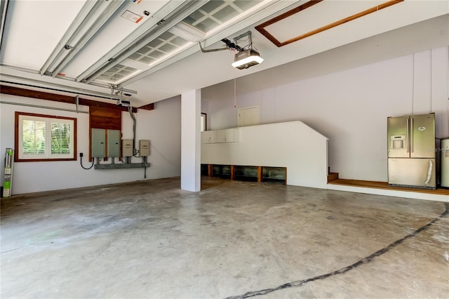 garage with a garage door opener, electric panel, and stainless steel refrigerator with ice dispenser