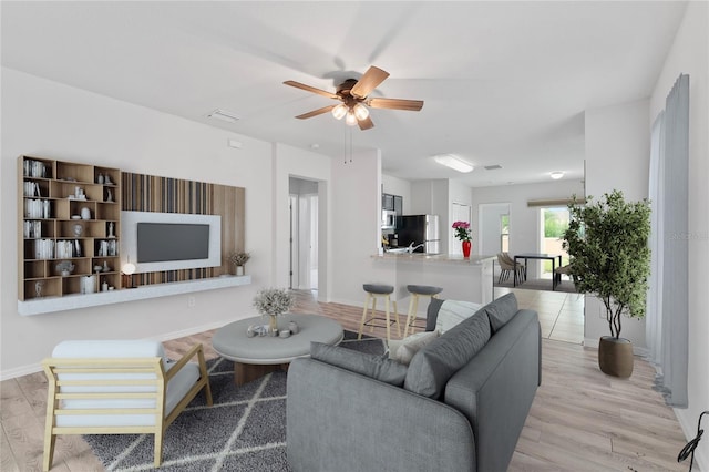 living room with ceiling fan and light wood-type flooring