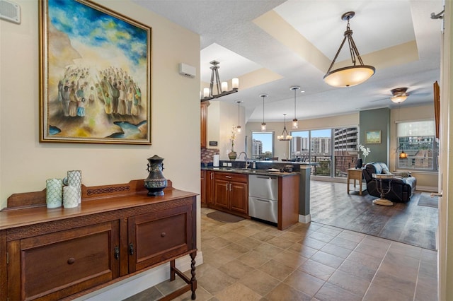 kitchen with kitchen peninsula, a tray ceiling, light tile flooring, and decorative light fixtures