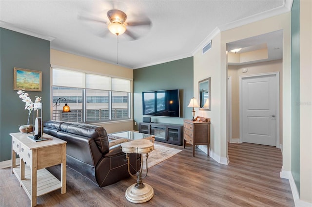 living room featuring hardwood / wood-style flooring, crown molding, ceiling fan, and a textured ceiling