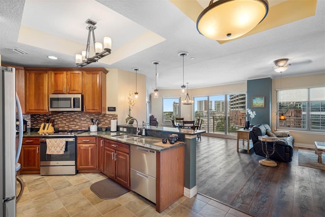 kitchen with kitchen peninsula, stainless steel appliances, light tile floors, and sink