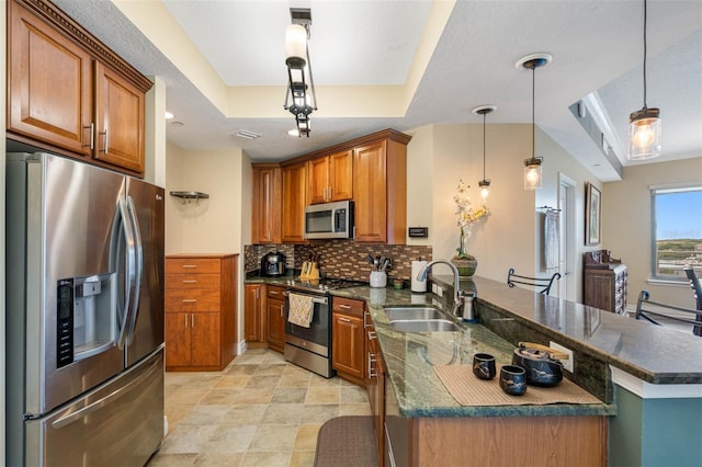 kitchen featuring kitchen peninsula, hanging light fixtures, stainless steel appliances, tasteful backsplash, and a tray ceiling