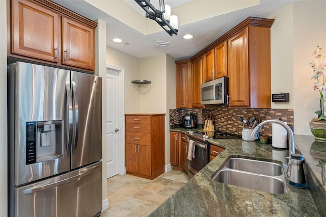 kitchen with light tile floors, sink, tasteful backsplash, stainless steel appliances, and dark stone countertops