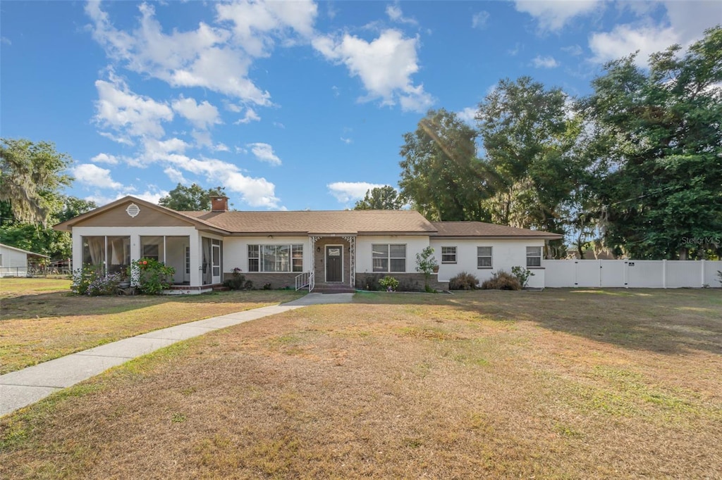 single story home featuring a sunroom and a front lawn