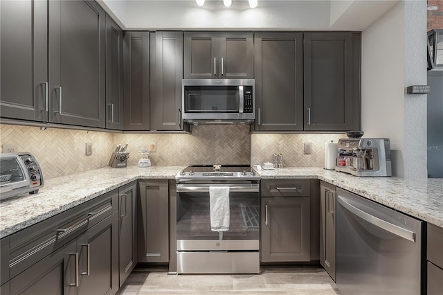 kitchen featuring tasteful backsplash, stainless steel appliances, and light stone countertops