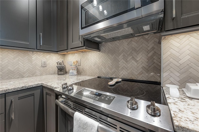 kitchen featuring light stone counters, tasteful backsplash, and electric stove