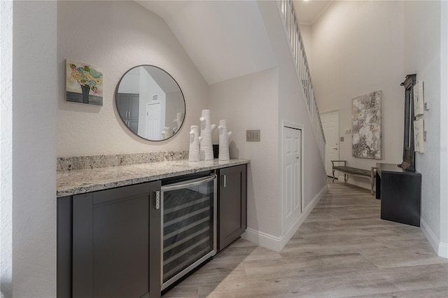 bathroom featuring wood-type flooring, vaulted ceiling, vanity, and wine cooler