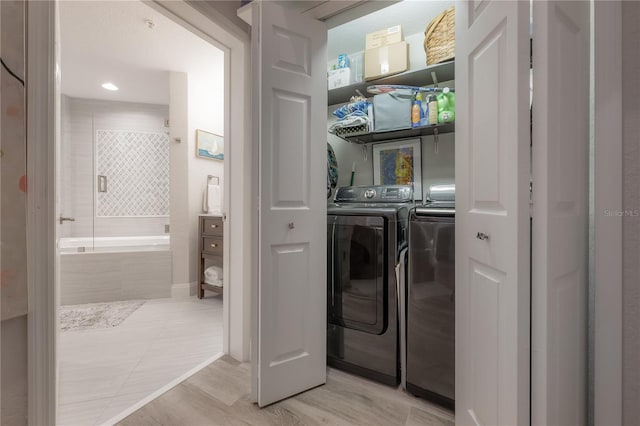 clothes washing area featuring washer and clothes dryer and light tile floors