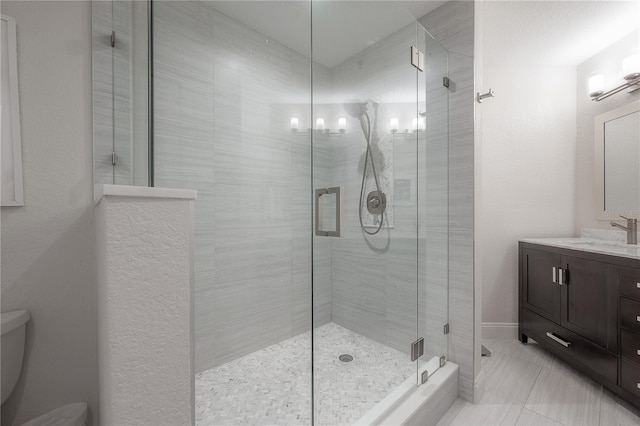 bathroom featuring a shower with door, toilet, vanity with extensive cabinet space, and tile flooring