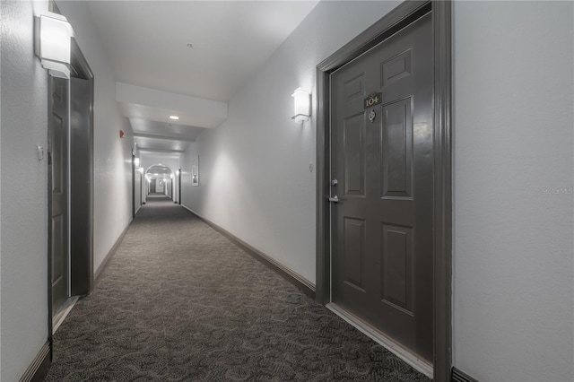 corridor featuring dark colored carpet