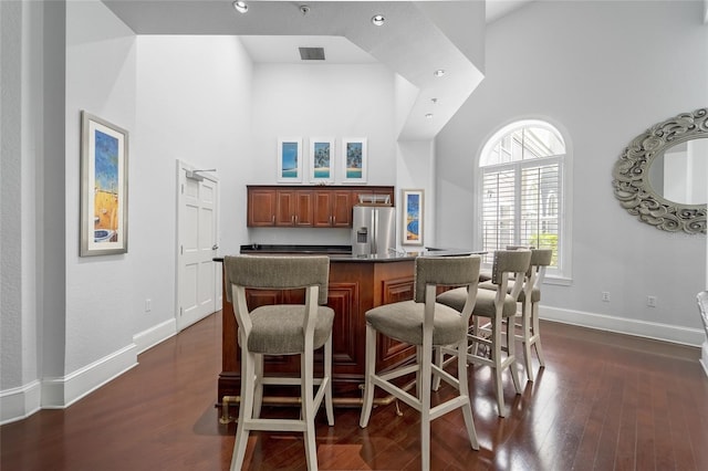 kitchen featuring high vaulted ceiling, stainless steel fridge with ice dispenser, and dark wood-type flooring