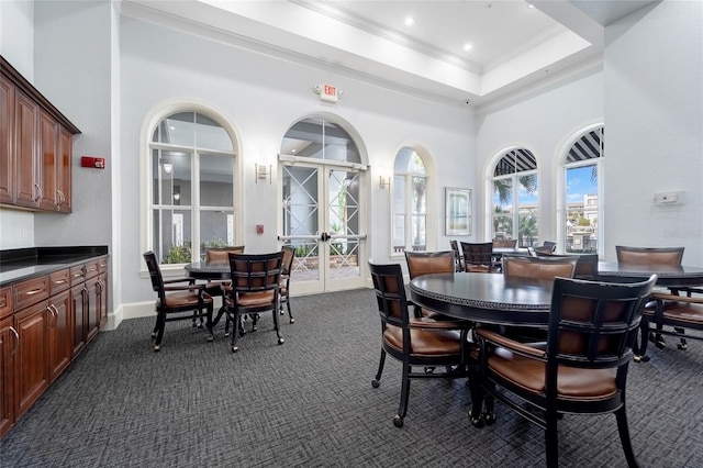 carpeted dining space featuring plenty of natural light, french doors, a tray ceiling, and a towering ceiling