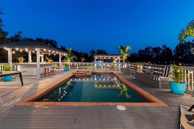 pool at night featuring a gazebo and a deck