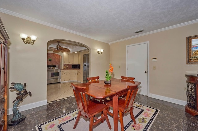 dining space with a textured ceiling, dark tile patterned floors, ceiling fan, and ornamental molding