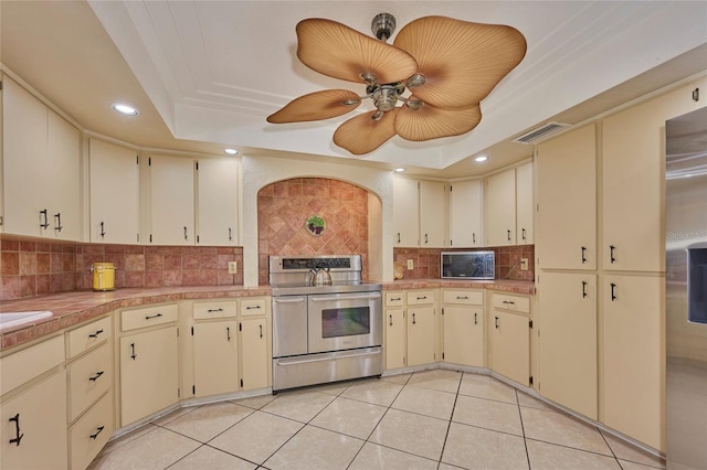 kitchen with cream cabinetry, a tray ceiling, and stainless steel range with electric cooktop