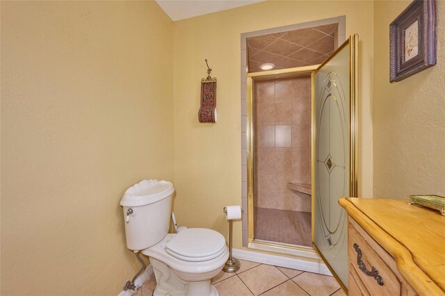 bathroom with tile patterned flooring, toilet, and a shower with shower door