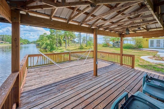 wooden deck featuring a water view and a lawn