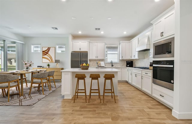 kitchen featuring white cabinets, a center island, custom exhaust hood, and black appliances