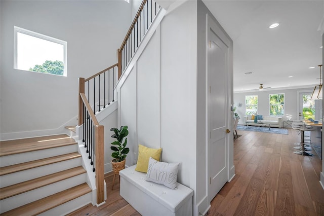 stairs with wood-type flooring and ceiling fan