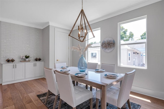 dining room with light wood-type flooring, ornamental molding, and an inviting chandelier