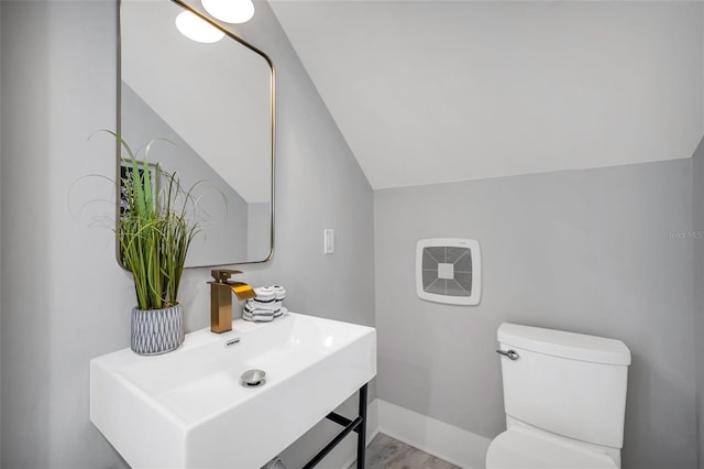 bathroom featuring hardwood / wood-style flooring, sink, toilet, and lofted ceiling