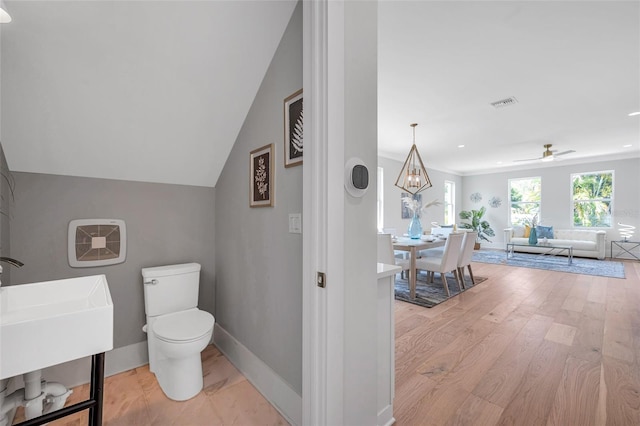 bathroom with wood-type flooring, toilet, sink, and ceiling fan with notable chandelier