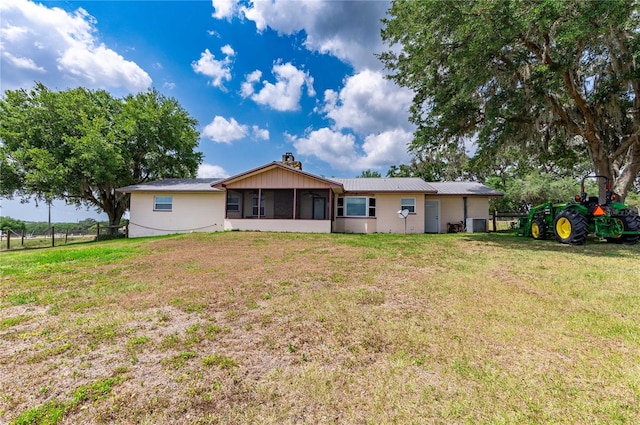 rear view of property featuring a sunroom, a yard, a chimney, and fence