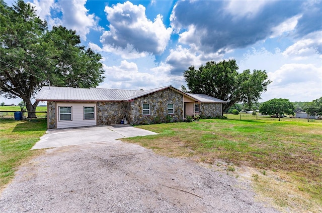 view of front of house featuring stone siding, metal roof, a front lawn, and fence