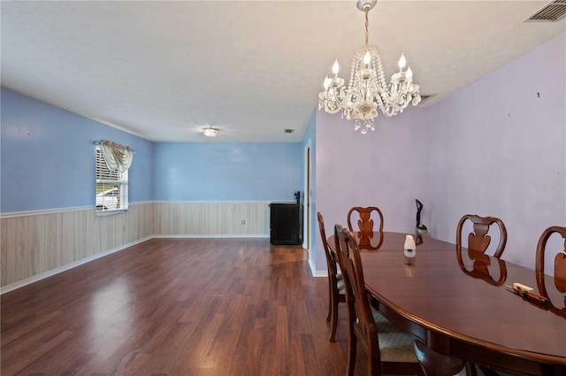 dining area featuring a wainscoted wall, a textured ceiling, visible vents, and dark wood-style flooring