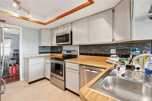 kitchen with light tile patterned flooring, stainless steel appliances, white cabinets, and sink