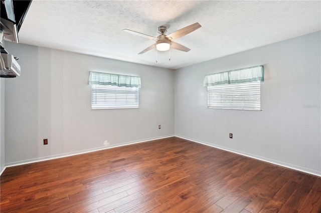 unfurnished room featuring dark wood-type flooring, ceiling fan, a textured ceiling, and baseboards