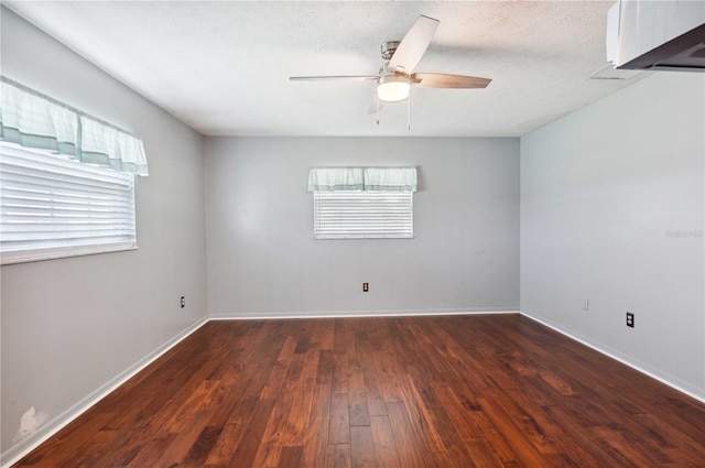 empty room with dark wood-style floors, a textured ceiling, baseboards, and a ceiling fan