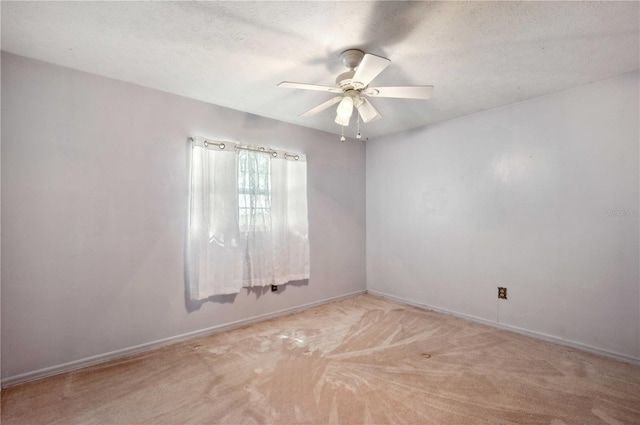 unfurnished room with a ceiling fan, light carpet, a textured ceiling, and baseboards