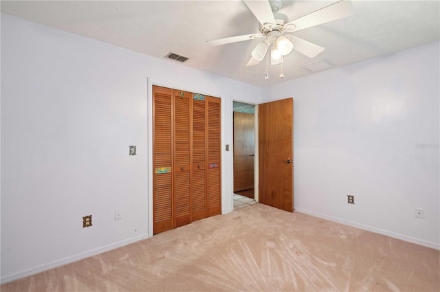 unfurnished bedroom with baseboards, visible vents, light colored carpet, ceiling fan, and a closet