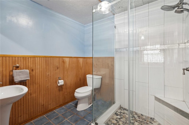 full bath with a textured ceiling, toilet, wainscoting, tile patterned floors, and a stall shower