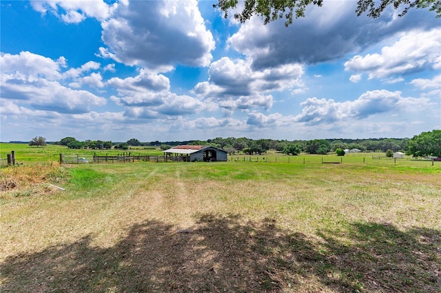 view of yard with a carport, a rural view, an outdoor structure, and fence