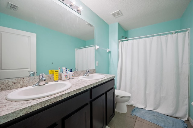 bathroom with toilet, vanity with extensive cabinet space, tile flooring, a textured ceiling, and double sink