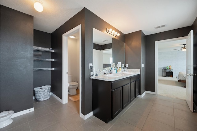 bathroom with dual bowl vanity, toilet, tile floors, and ceiling fan