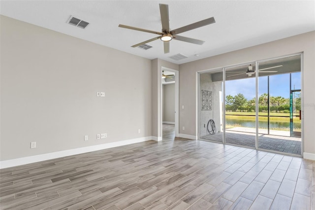 unfurnished room featuring ceiling fan and a water view