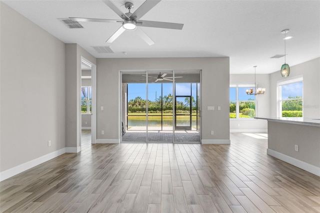 empty room featuring ceiling fan with notable chandelier and a water view