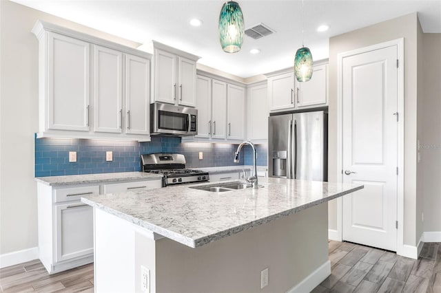 kitchen with hanging light fixtures, sink, an island with sink, and stainless steel appliances