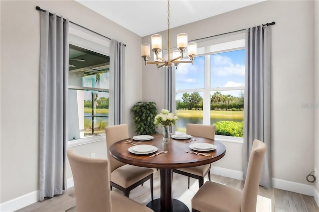 dining area featuring a water view, light wood-type flooring, and a notable chandelier