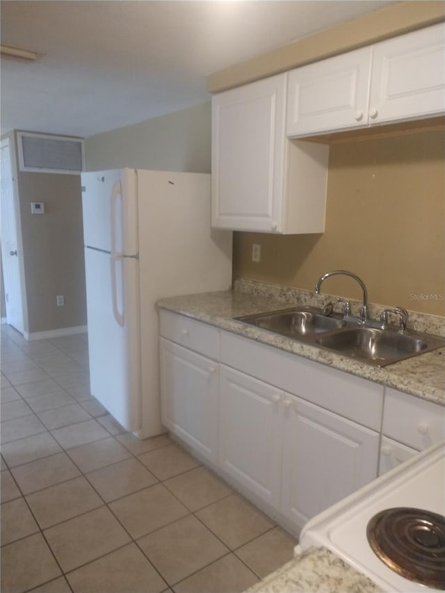 kitchen featuring white fridge, light stone countertops, white cabinets, sink, and light tile floors